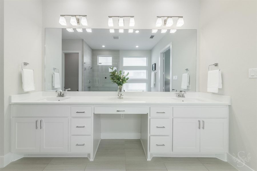 Expansive dual vanity offers abundant counter space, extensive storage and a dedicated seated makeup area. An oversized mirror and modern lighting complete this beautifully appointed primary bath. Expansive dual vanity offers abundant counter space, extensive storage and a dedicated seated makeup area. An oversized mirror and modern lighting complete this beautifully appointed primary bath.