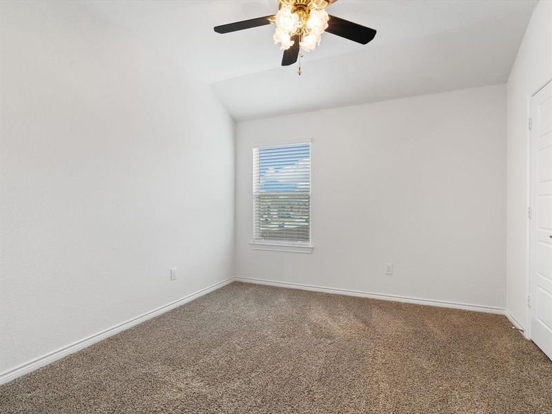 Carpeted empty room featuring vaulted ceiling and ceiling fan