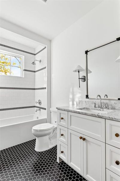 Bathroom featuring vanity, bathtub / shower combination, and dark tile patterned floors Bathroom featuring vanity, bathtub / shower combination, and dark tile patterned floors