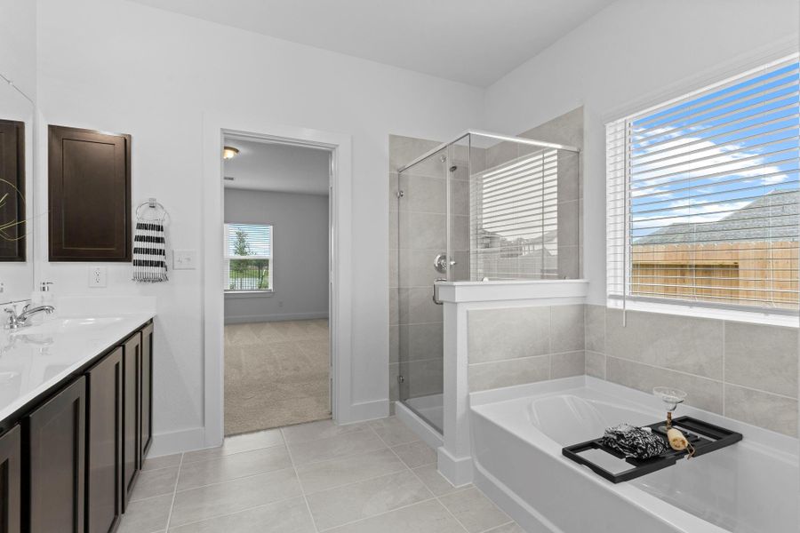Another view of the primary bath reveals its thoughtful layout with a dual vanity, deep soaking tub, and walk-in shower—all connected seamlessly to the private bedroom retreat. Large shower for that shower person! Never run out of hot water with the Tankless/On-Demand H2O Heater! Beautiful large tile flooring! Another view of the primary bath reveals its thoughtful layout with a dual vanity, deep soaking tub, and walk-in shower—all connected seamlessly to the private bedroom retreat. Large shower for that shower person! Never run out of hot water with the Tankless/On-Demand H2O Heater! Beautiful large tile flooring!