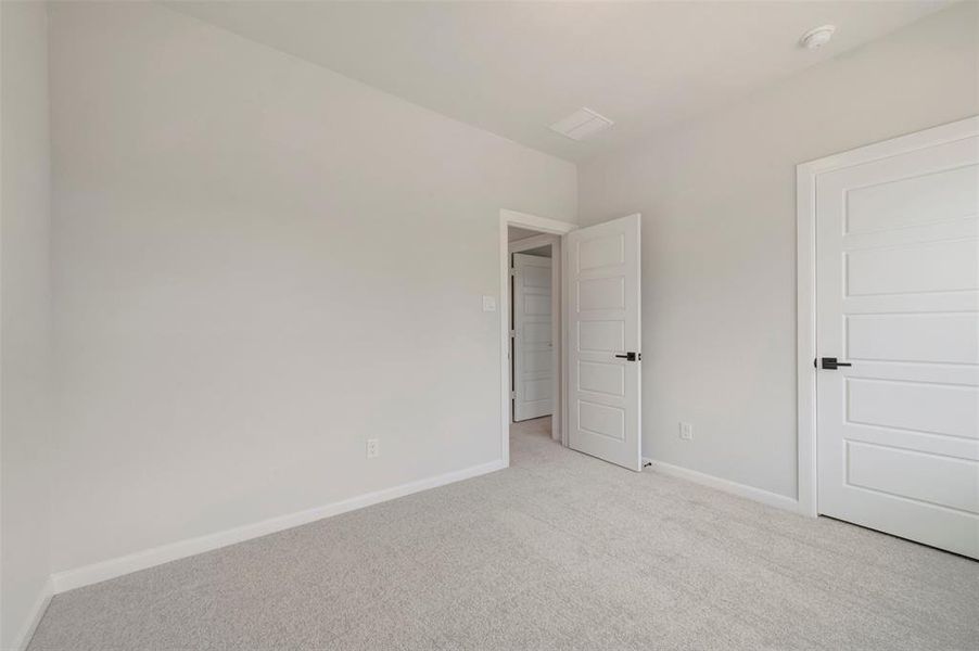 Neutral tone carpeted room with white paneled doors and matte black hardware Neutral tone carpeted room with white paneled doors and matte black hardware