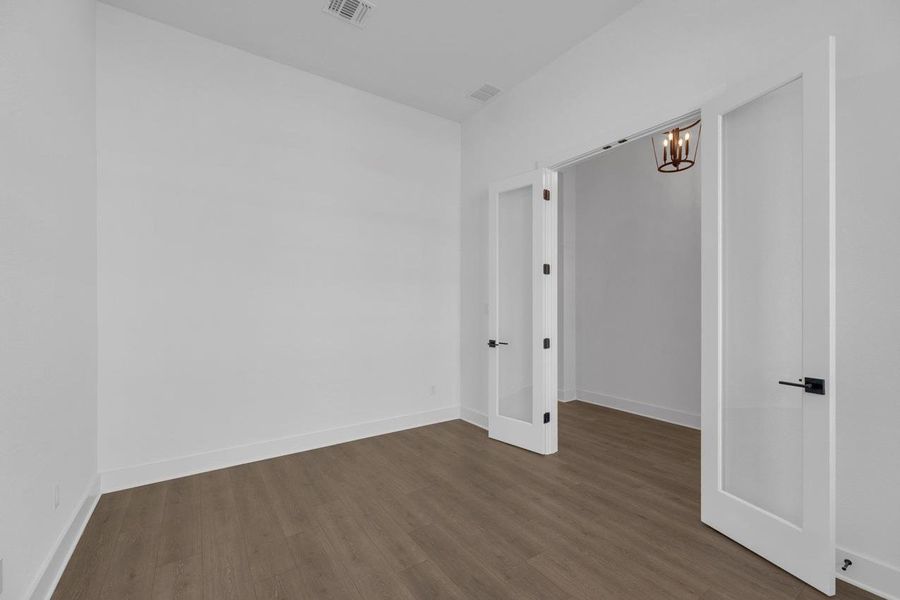 Empty room with dark wood-type flooring and a chandelier Empty room with dark wood-type flooring and a chandelier