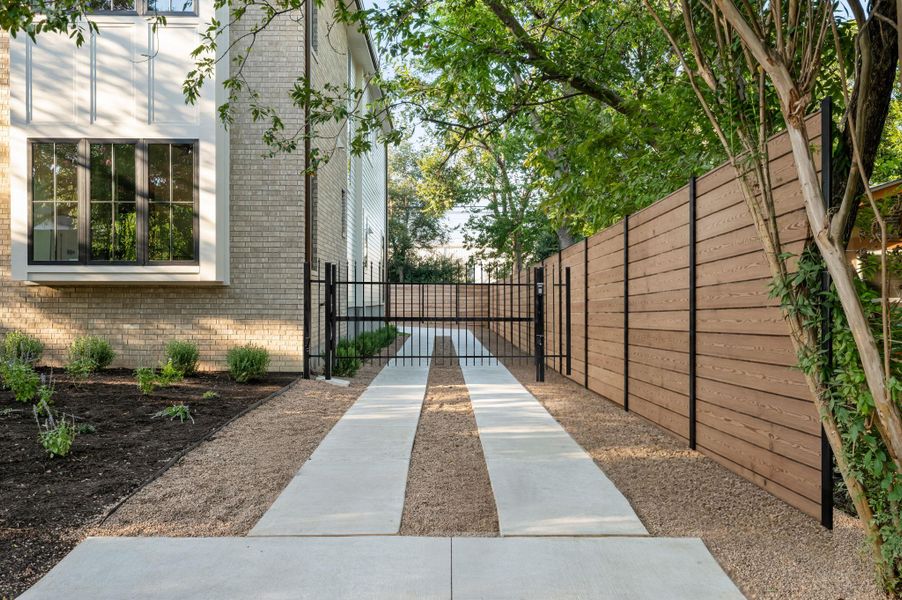 A private gated driveway offers secure entry alongside a contemporary horizontal plank fence.