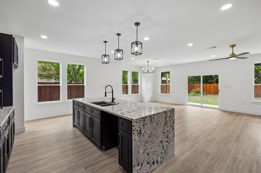 Expansive kitchen island with a waterfall countertop and integrated sink, complemented by dark cabinetry Expansive kitchen island with a waterfall countertop and integrated sink, complemented by dark cabinetry
