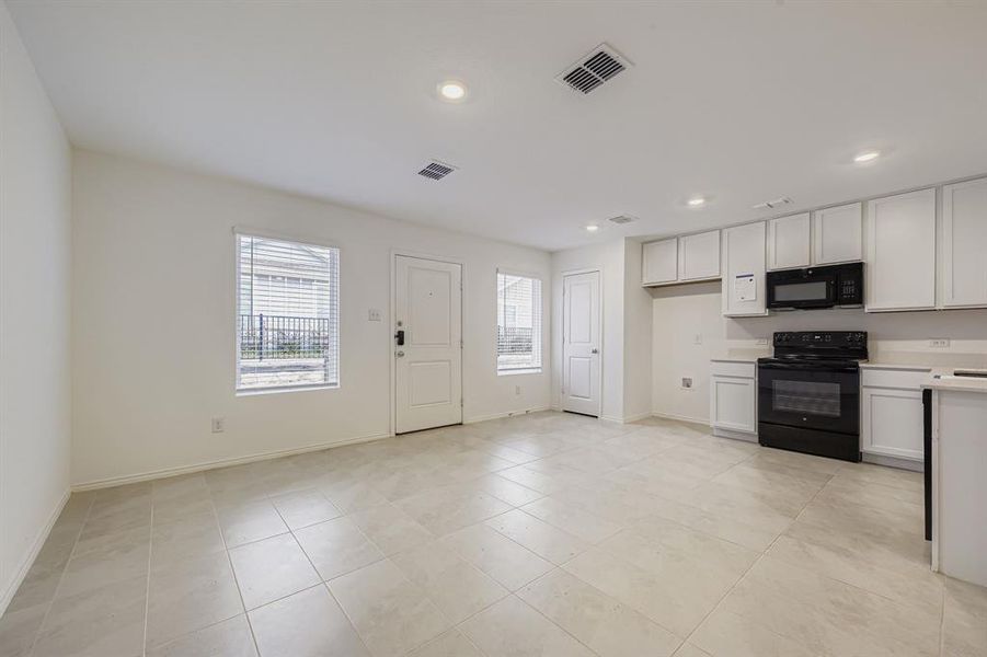 Kitchen featuring light countertops, white cabinets, black appliances, recessed lighting, and open floor plan