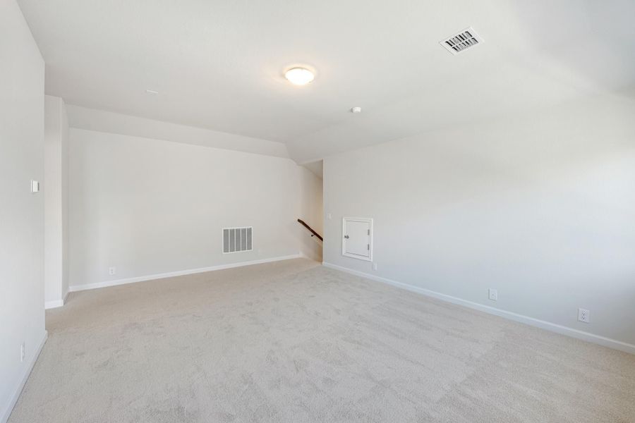 Empty bonus room with beige carpet, white walls, angled ceiling, and staircase opening