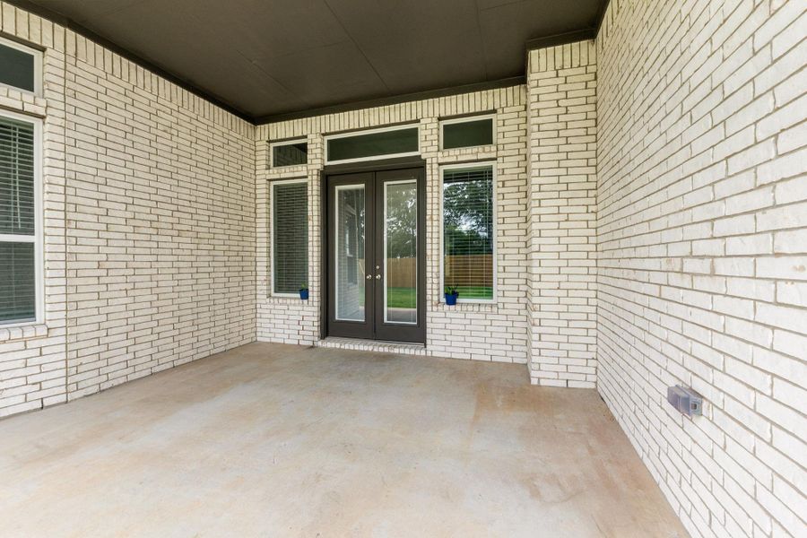 Property entrance with brick siding, french doors, and a patio Property entrance with brick siding, french doors, and a patio