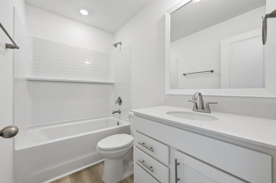 Bathroom with washtub / shower combination, vanity, light wood-type flooring, and recessed lighting Bathroom with washtub / shower combination, vanity, light wood-type flooring, and recessed lighting