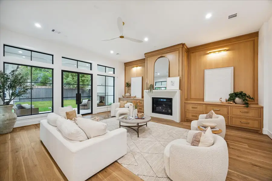 Floor-to-ceiling windows frame backyard views and flood the room with natural light. Clean architectural lines balance warmth and modern simplicity. The 12 ft ceilings on the first floor heighten the sense of openness.