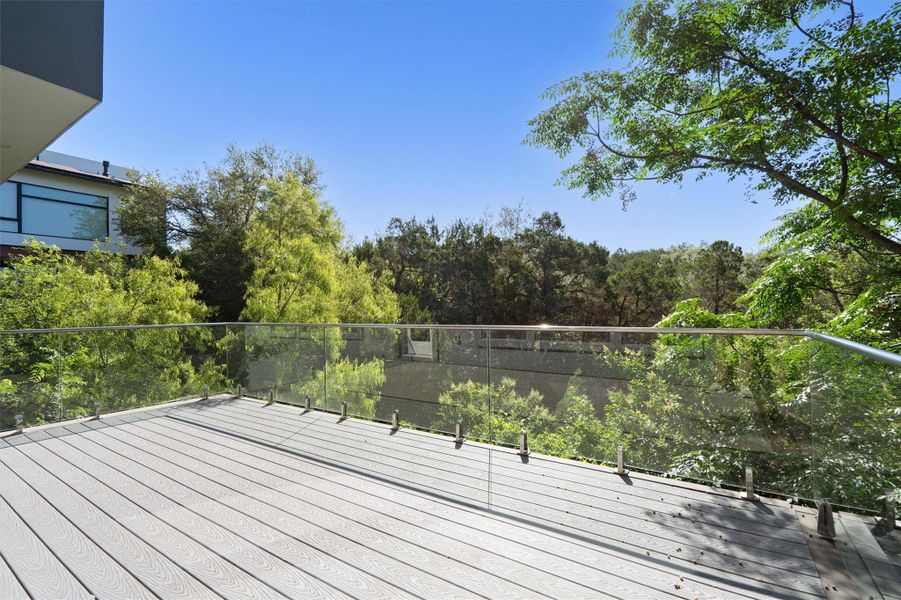 A spacious outdoor deck with glass railings provides serene forest views and a private atmosphere. A spacious outdoor deck with glass railings provides serene forest views and a private atmosphere.