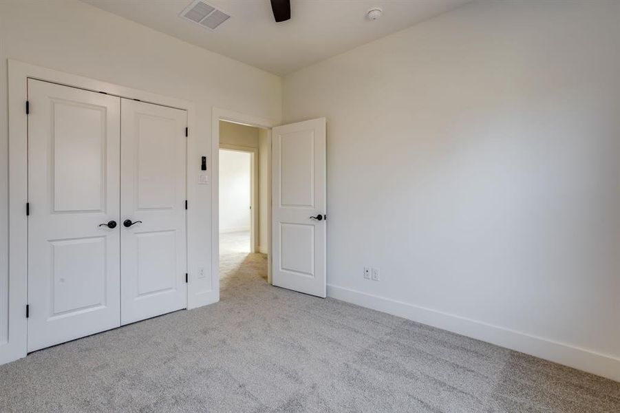 Unfurnished bedroom featuring carpet floors, a closet, and a ceiling fan