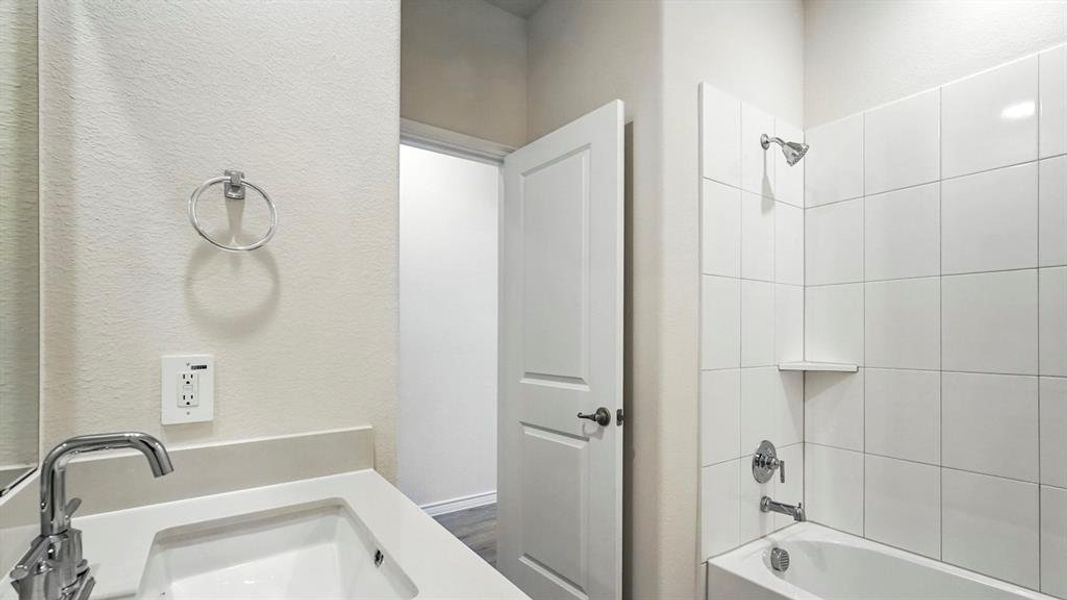 Bathroom featuring a white vanity with an integrated sink, chrome faucet, and coordinating towel ring Bathroom featuring a white vanity with an integrated sink, chrome faucet, and coordinating towel ring