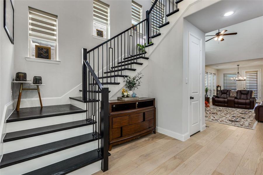 Stairway with healthy amount of natural light, ceiling fan, hardwood / wood-style flooring, suspended lighting, and a high ceiling