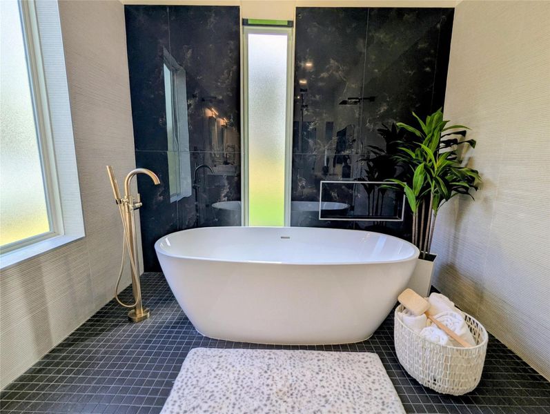 This bathroom features a modern freestanding bathtub against a striking black accent wall. It includes a sleek gold faucet and frosted windows for privacy. The dark tiled floor contrasts with the light walls, adding a touch of elegance. This bathroom features a modern freestanding bathtub against a striking black accent wall. It includes a sleek gold faucet and frosted windows for privacy. The dark tiled floor contrasts with the light walls, adding a touch of elegance.