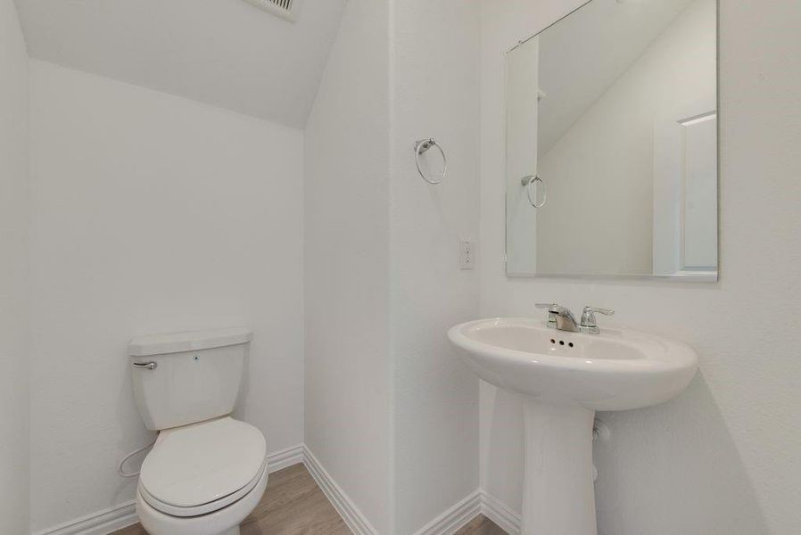 Half bath featuring toilet and wood finished floors Half bath featuring toilet and wood finished floors