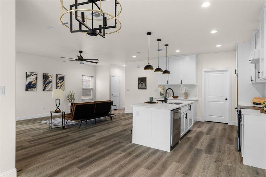 Kitchen with a center island with sink, sink, pendant lighting, and white cabinets