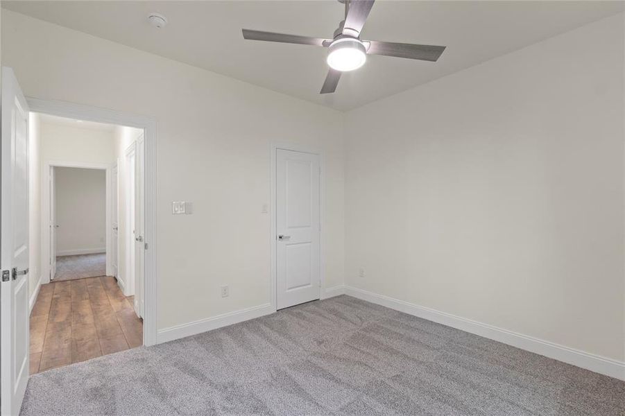 Neutral-toned interior room featuring light gray carpeting and a contemporary ceiling fan with integrated lighting Neutral-toned interior room featuring light gray carpeting and a contemporary ceiling fan with integrated lighting