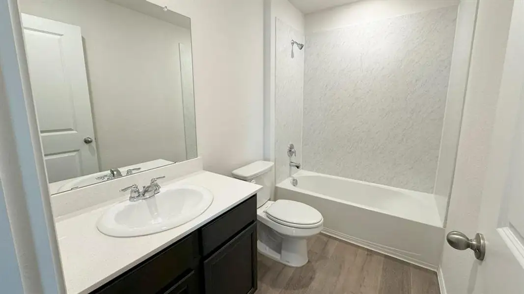 Bathroom with vanity, dark wood-type flooring, and shower / tub combination