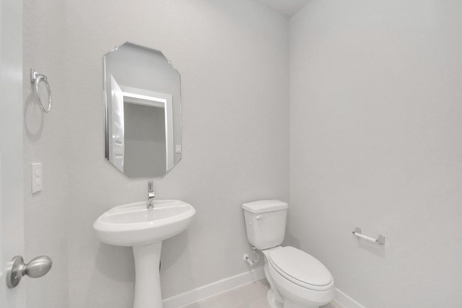 This half bathroom features a stylish pedestal sink, modern hardware, and bright recessed lighting, creating a sleek and inviting space. Sample photo of completed home with similar floor plan. Actual colors and selections may vary.