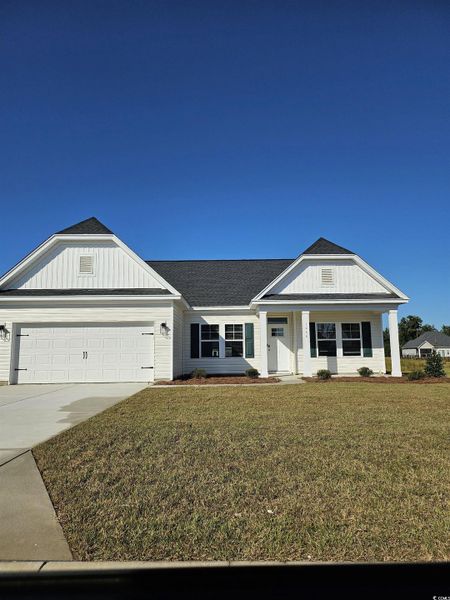 View of front of house featuring covered porch, driveway, an attached garage, a front yard, and roof with shingles
