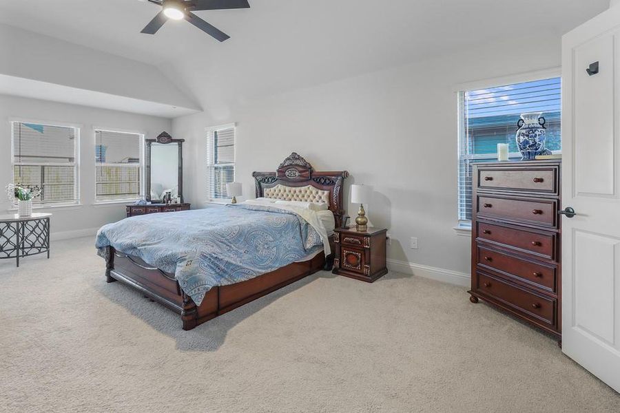 Bedroom with vaulted ceiling, light colored carpet, and a ceiling fan