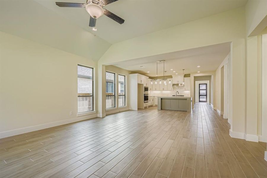 Unfurnished living room featuring light wood finished floors, recessed lighting, ceiling fan, and lofted ceiling