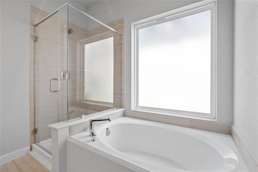 This master bathroom is definitely move-in ready! Featuring a framed walk-in shower with tile surround, separate garden tub for soaking after a long day!