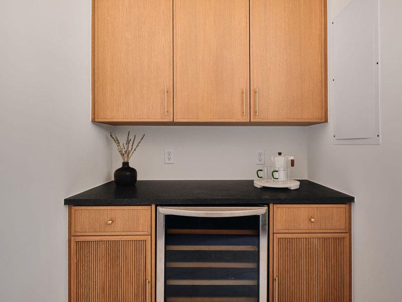 Bar featuring wine cooler and dark countertops