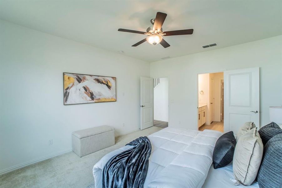 Bedroom featuring light carpet, a ceiling fan, and ensuite bath Bedroom featuring light carpet, a ceiling fan, and ensuite bath