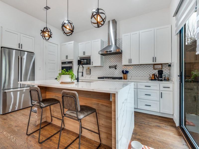 Kitchen featuring appliances with stainless steel finishes, light stone counters, pendant lighting, and white cabinetry