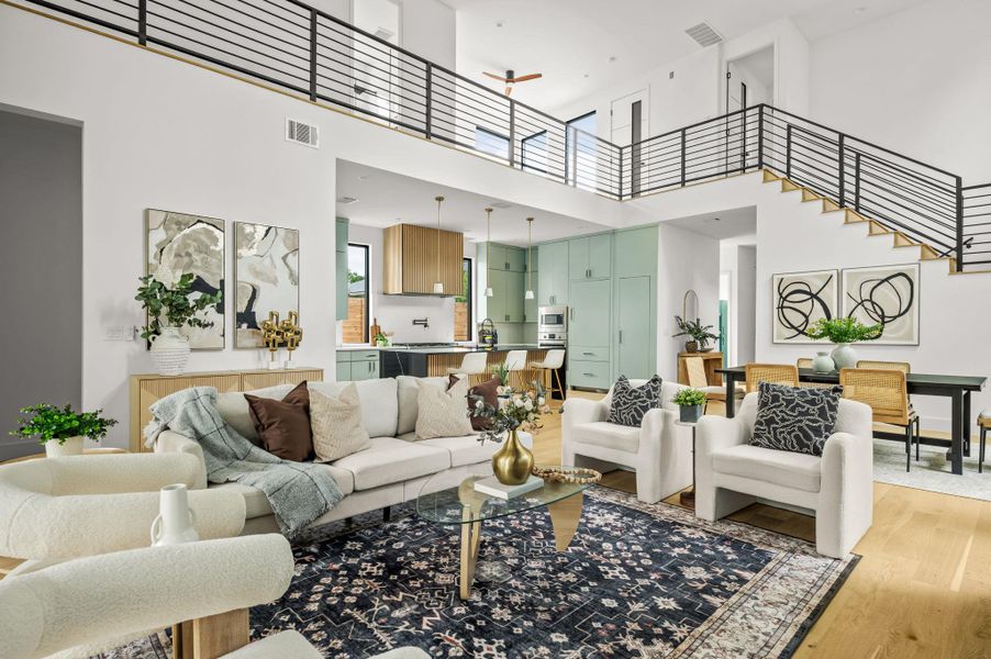 An open-concept living area features a modern kitchen, inviting seating, and elegant hardwood flooring, all beneath a high vaulted ceiling. An open-concept living area features a modern kitchen, inviting seating, and elegant hardwood flooring, all beneath a high vaulted ceiling.