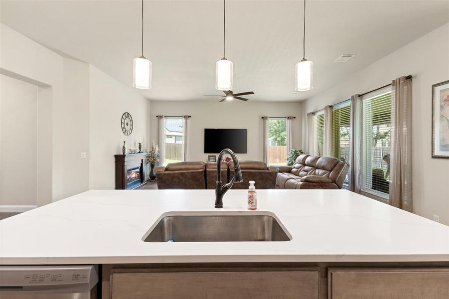Kitchen island featuring a stainless steel undermount sink, a matte black gooseneck faucet, and three pendant lights above Kitchen island featuring a stainless steel undermount sink, a matte black gooseneck faucet, and three pendant lights above