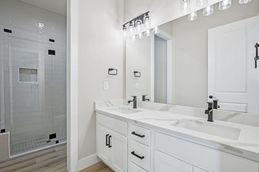 Bathroom with a shower stall, double vanity, and light wood-type flooring