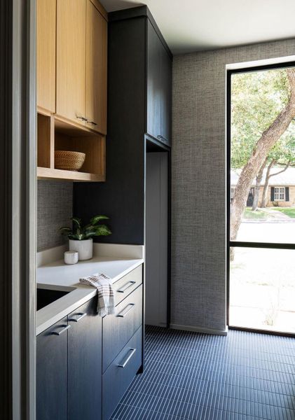 Most luxurious laundry and mud room ever! Ample stained white oak cabinets, gorgeous textured wallpaper, designer tile, quartz countertops and natural light.