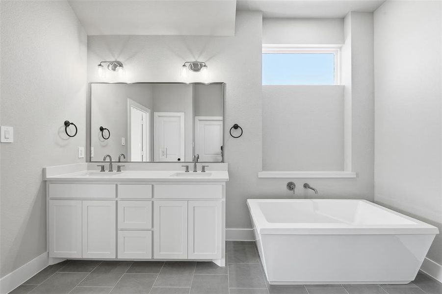 Full bathroom featuring double vanity, a freestanding tub, and dark tile patterned flooring Full bathroom featuring double vanity, a freestanding tub, and dark tile patterned flooring