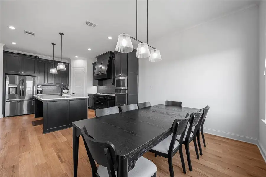 Dining area featuring light wood-style floors, ornamental molding, and recessed lighting Dining area featuring light wood-style floors, ornamental molding, and recessed lighting