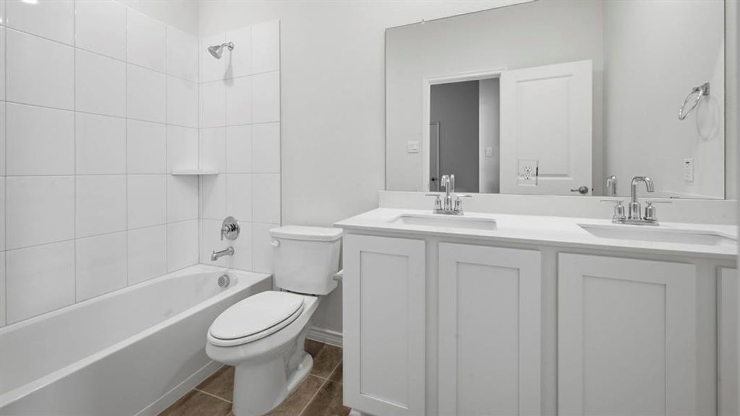 Full bathroom with double vanity and washtub / shower combination