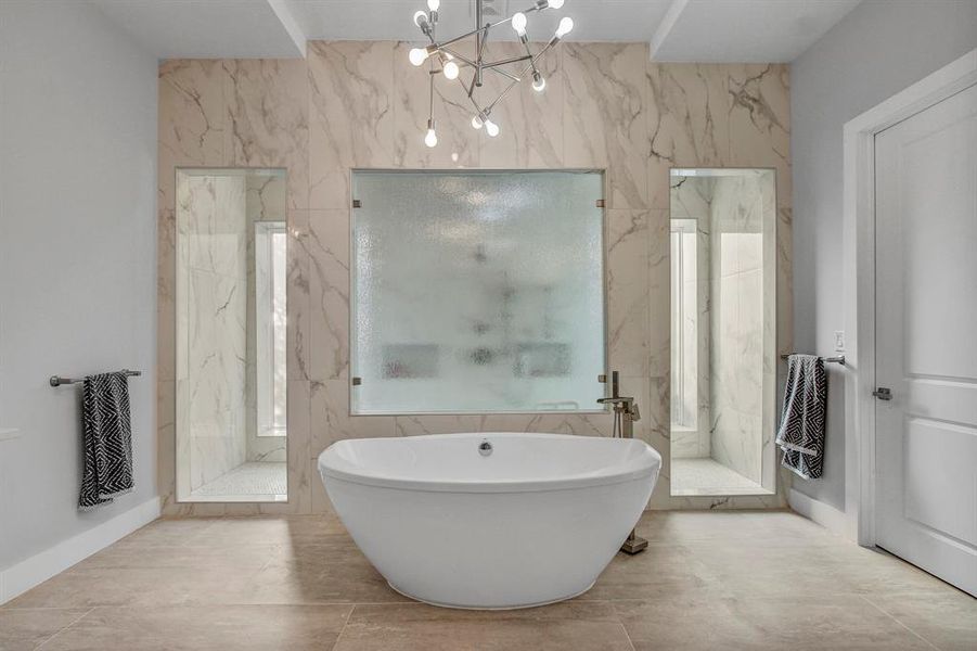Bathroom featuring a marble finish shower, a soaking tub, a chandelier, and tile walls