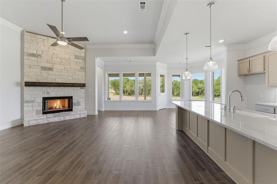 Unfurnished living room featuring a fireplace, dark wood-style floors, crown molding, ceiling fan, and recessed lighting