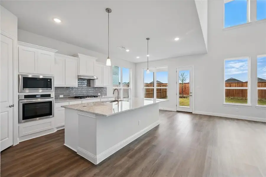 Kitchen with oven, gas cooktop, under cabinet range hood, a sink, and built in microwave