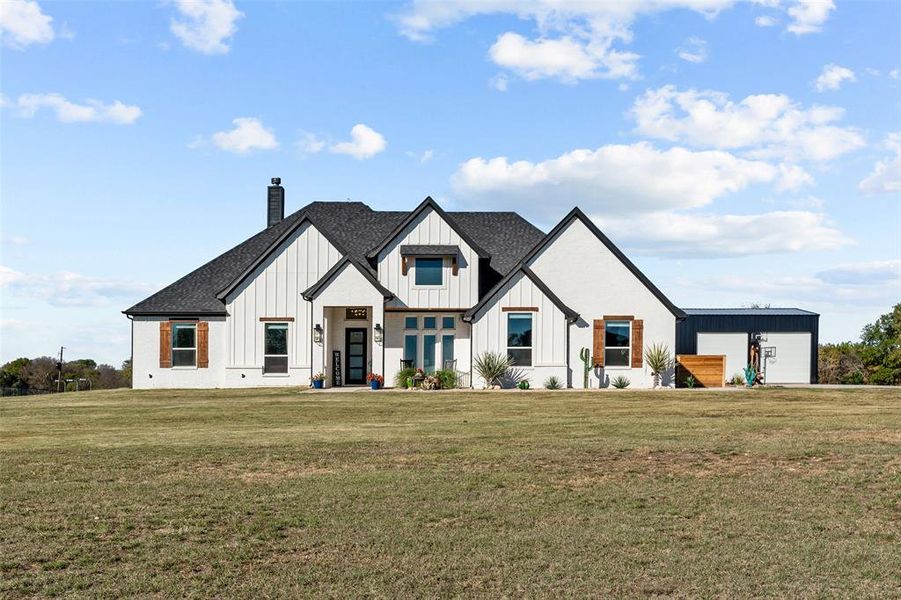 Modern farmhouse featuring an outbuilding and a front yard