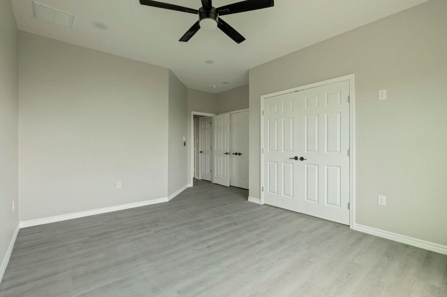 Unfurnished bedroom featuring wood finished floors, a ceiling fan, and a closet