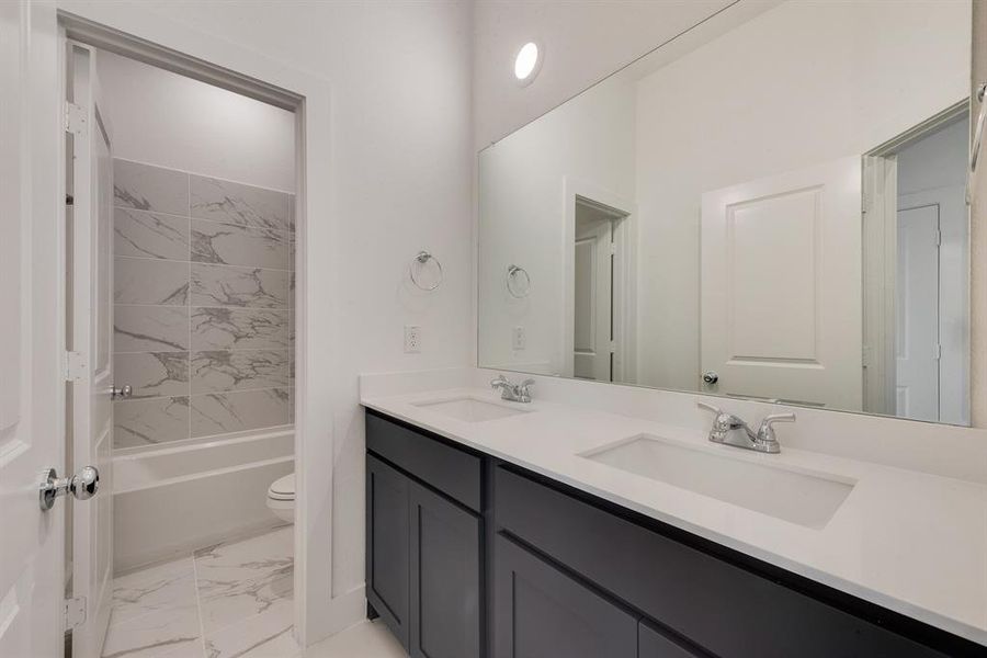 Bathroom featuring light marble finish flooring, double vanity, and shower combination Bathroom featuring light marble finish flooring, double vanity, and shower combination