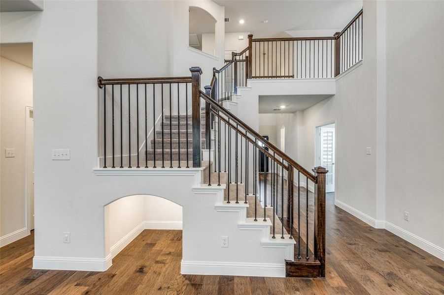 Stairway featuring wood finished floors, baseboards, and a towering ceiling