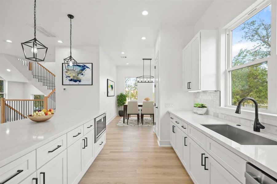 Virtually Staged: This kitchen includes under cabinet lighting and outlets, and luxury vinyl plank floors. Photos are from a similar unit in the development.