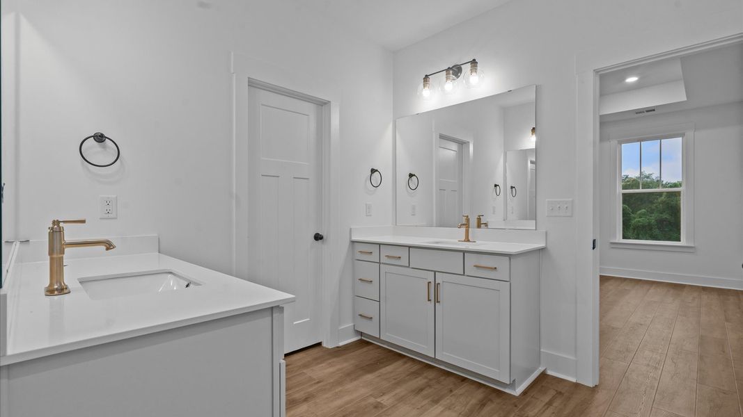 Notable primary suite with separate vanities and tiled walk-in shower in this prime Greenville townhome