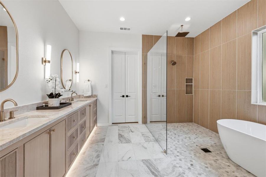 Bathroom featuring double vanity, a freestanding tub, a walk in shower, light marble finish floors, and recessed lighting