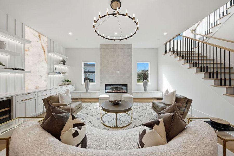 This sophisticated family room is a masterclass in modern luxury, blending clean architectural lines with warm, organic textures. Designed for both high-end entertaining and cozy evenings, the space features a striking floor-to-ceiling tiled fireplace flanked by custom built-ins and elegant window seating