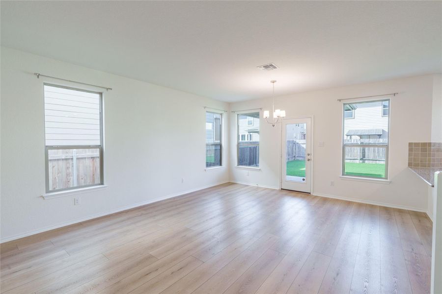 A spacious dining area with light wood flooring and backyard access creates a welcoming atmosphere. A spacious dining area with light wood flooring and backyard access creates a welcoming atmosphere.