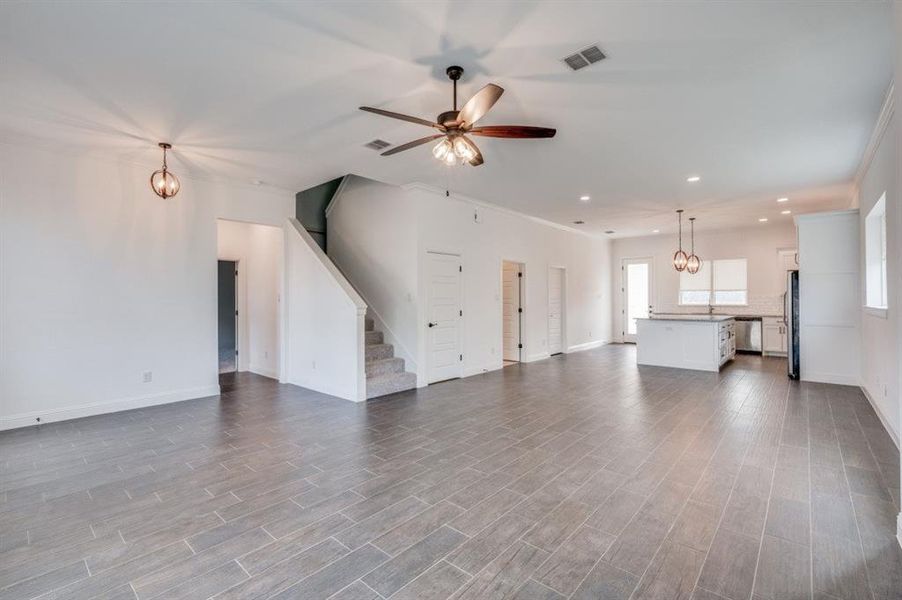 Unfurnished living room featuring ceiling fan with notable chandelier